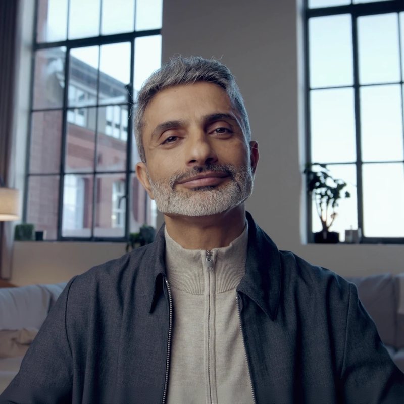 The Philosopher's avatar: a man with silver hair and a beard in a grey jacket, seated in a bright loft.